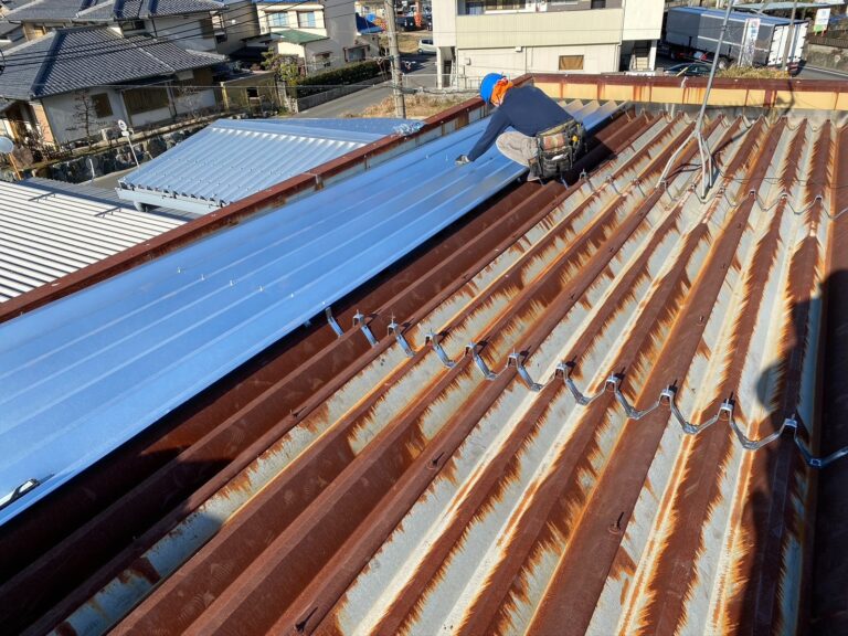 古い屋根の上からカバー工法で新しい屋根を貼り付けている作業中の写真